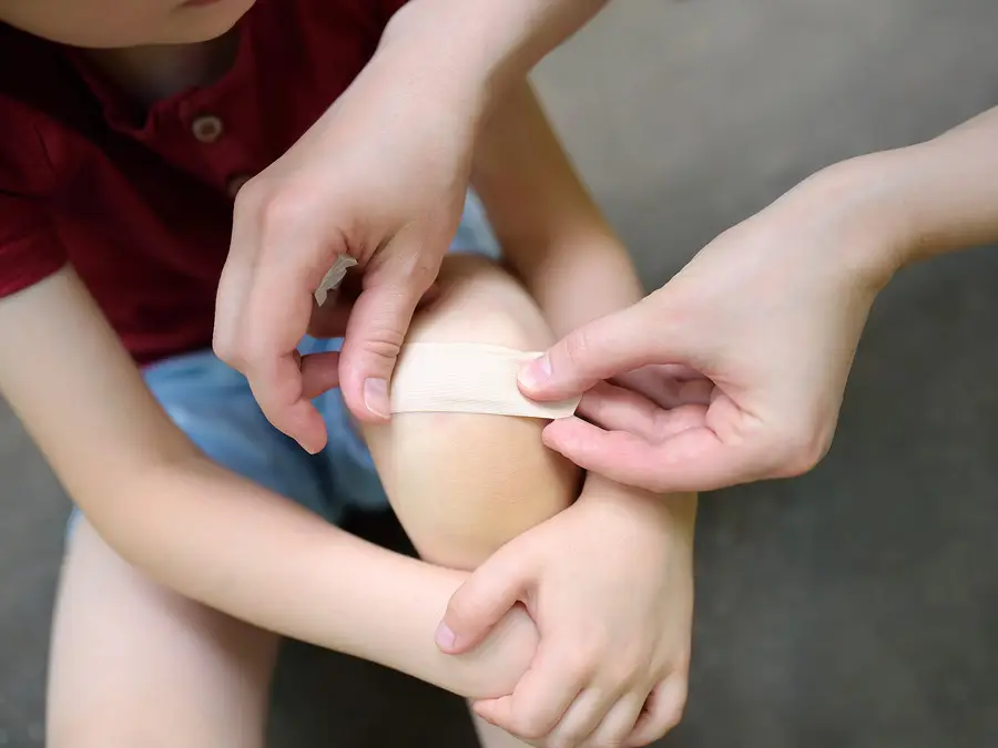 A person putting a bandage on a child's knee